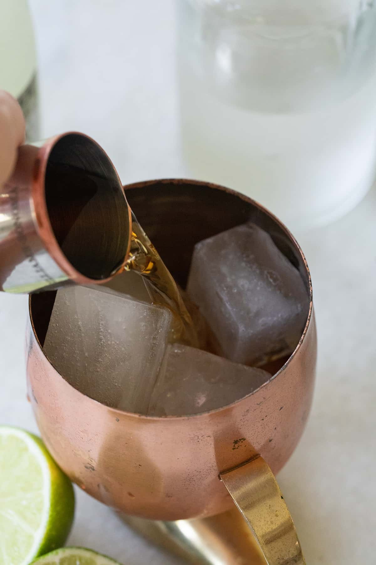 Pouring bourbon into a copper mug.