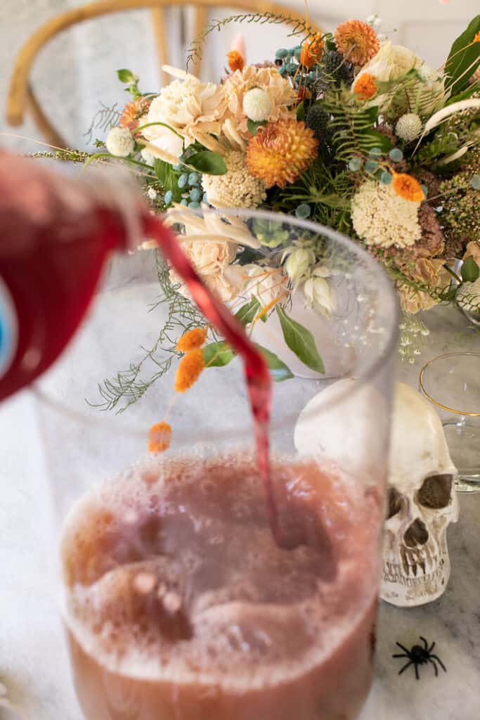 Pouring juice into a giant glass container.