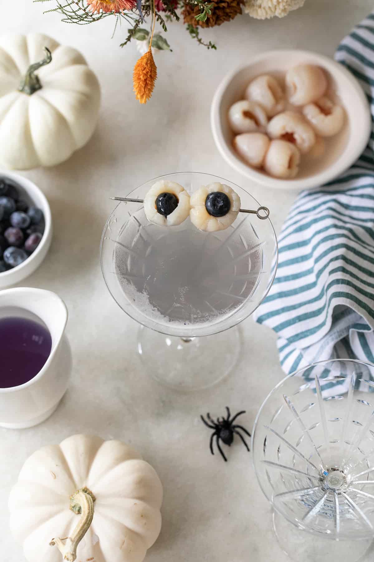 Lychee martini in a martini glass with spooky eyes.