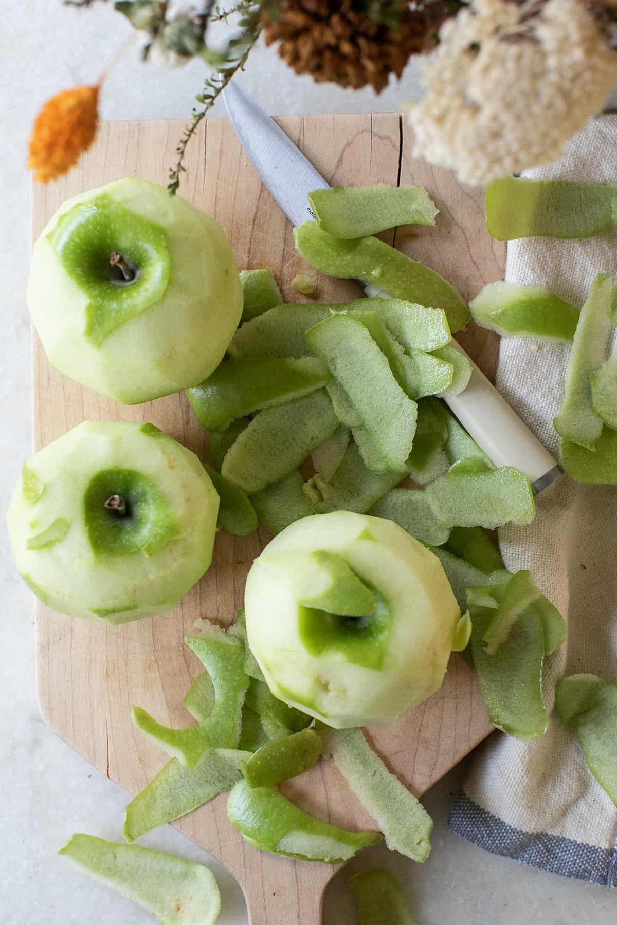 Peeled Granny Smith apples on a cutting board. 