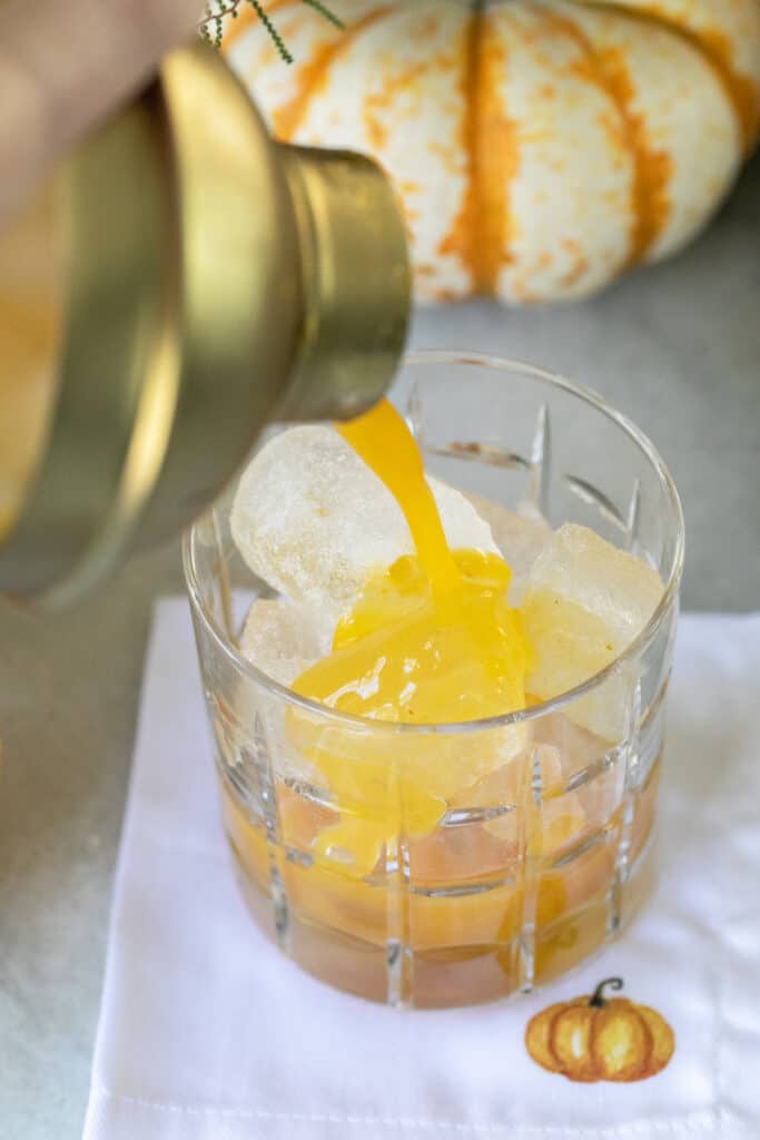 Pouring an orange margarita into a cocktail shaker.