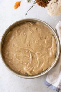 Upside down apple cake batter spread evenly over the top of apples.