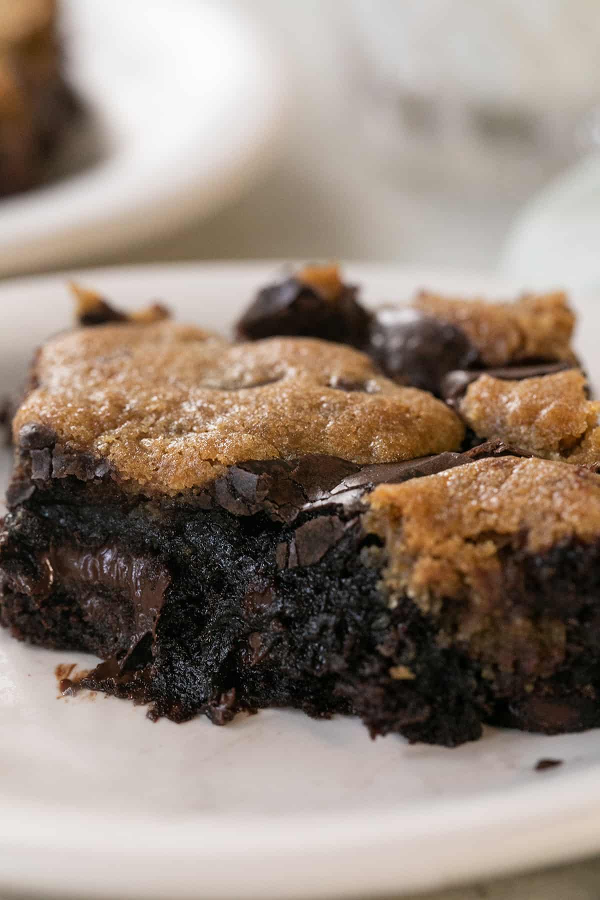 A gooey, chocolate brookie on a plate with a bite taken out of it.