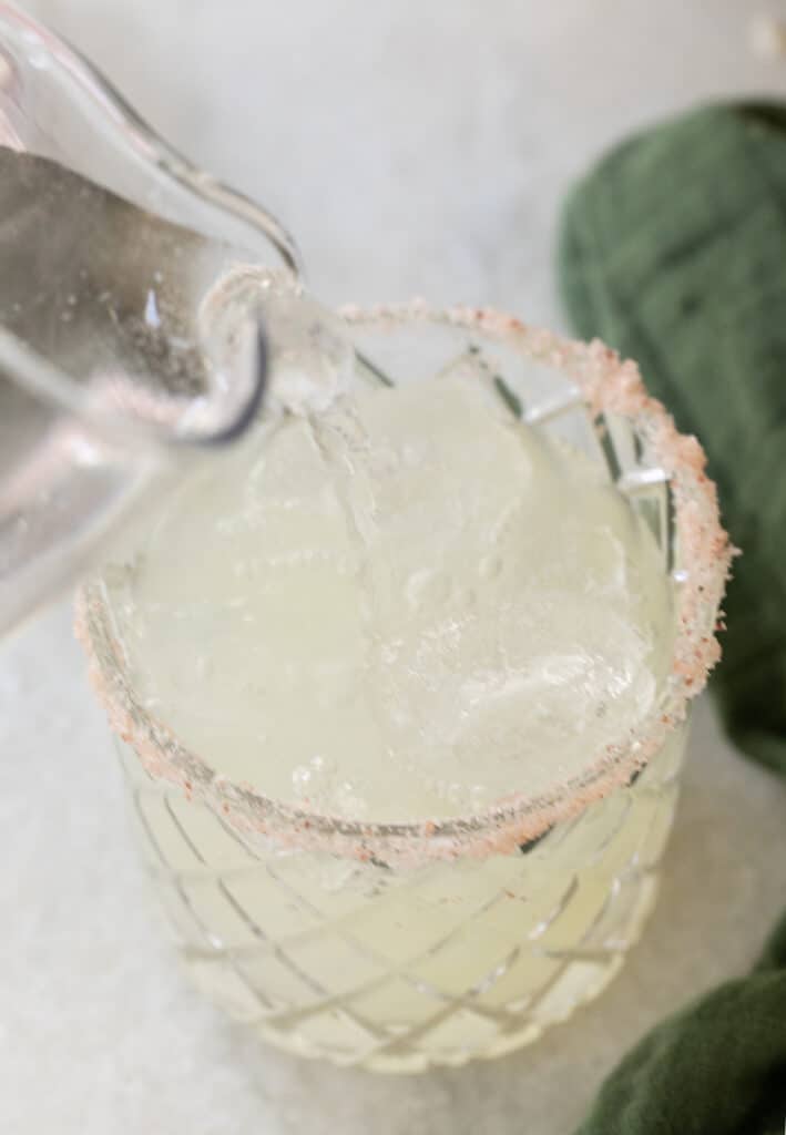 pouring club soda into a glass filled with fresh juice.