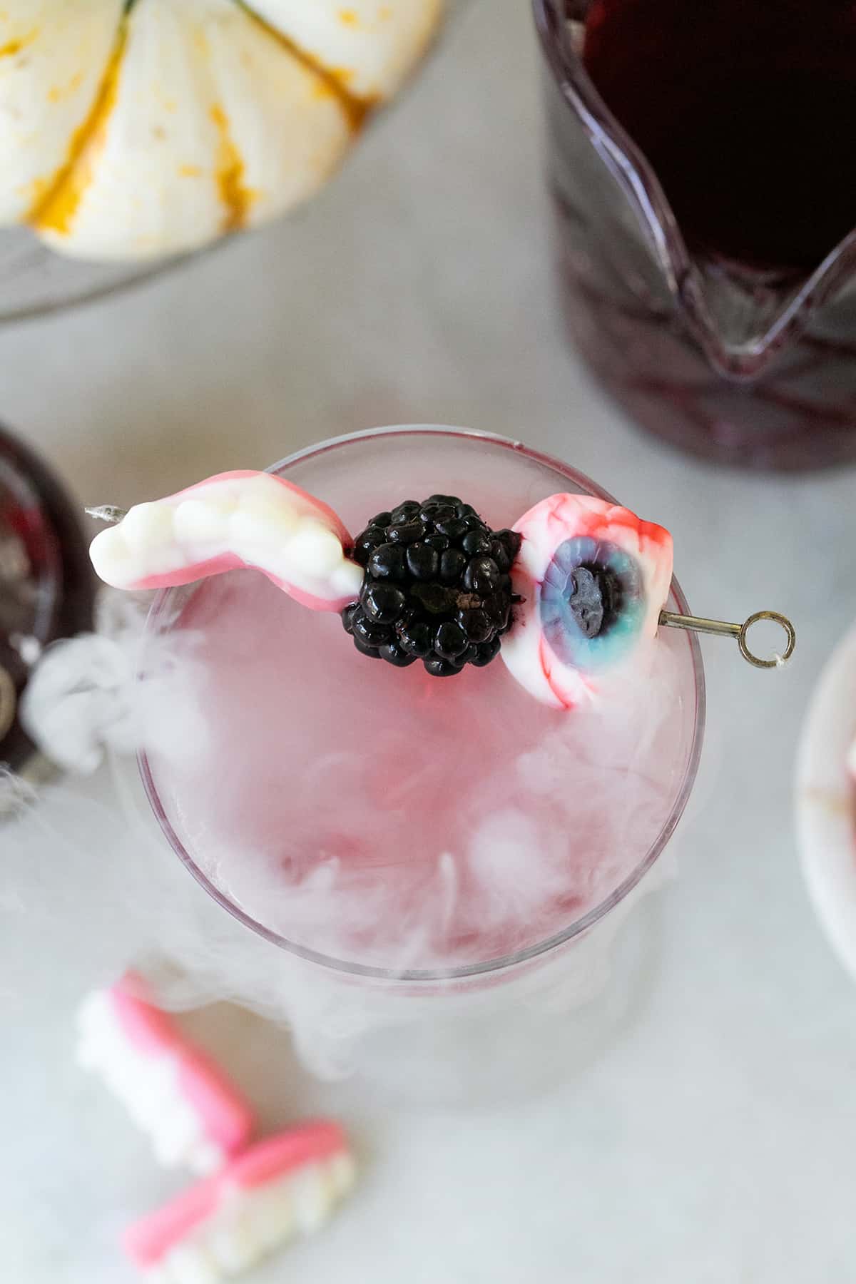 Cocktail with dry ice and gummy eye candy skewer.