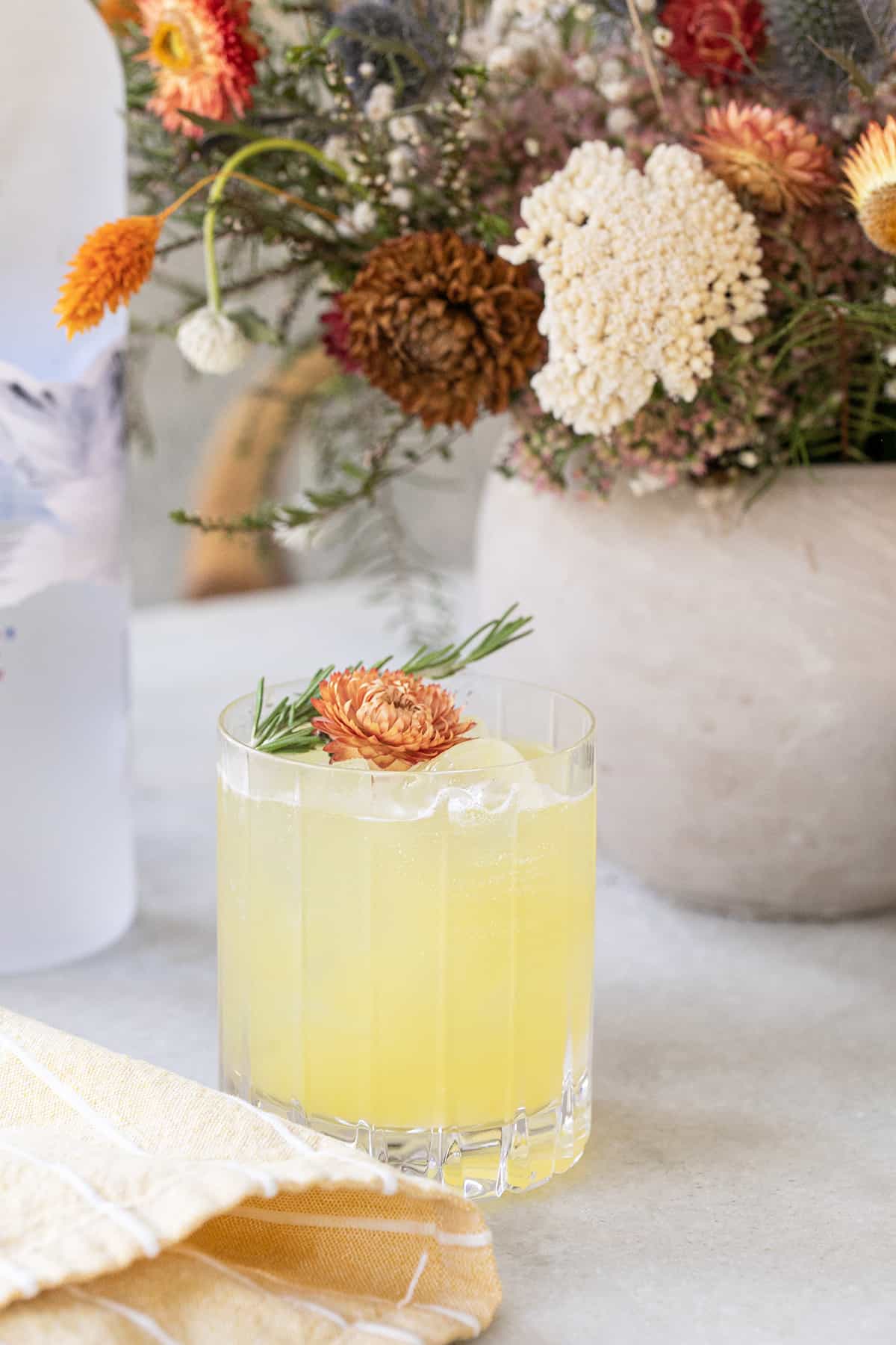 pineapple crush cocktail with flowers and a yellow napkin.