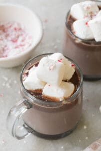 Peppermint mint hot chocolate in a clear mug with marshmallows and crushed candy canes.