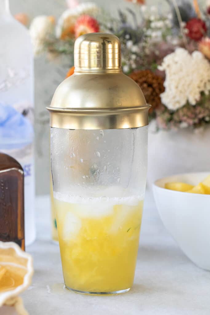 Pineapple juice in a cocktail shaker with ice.
