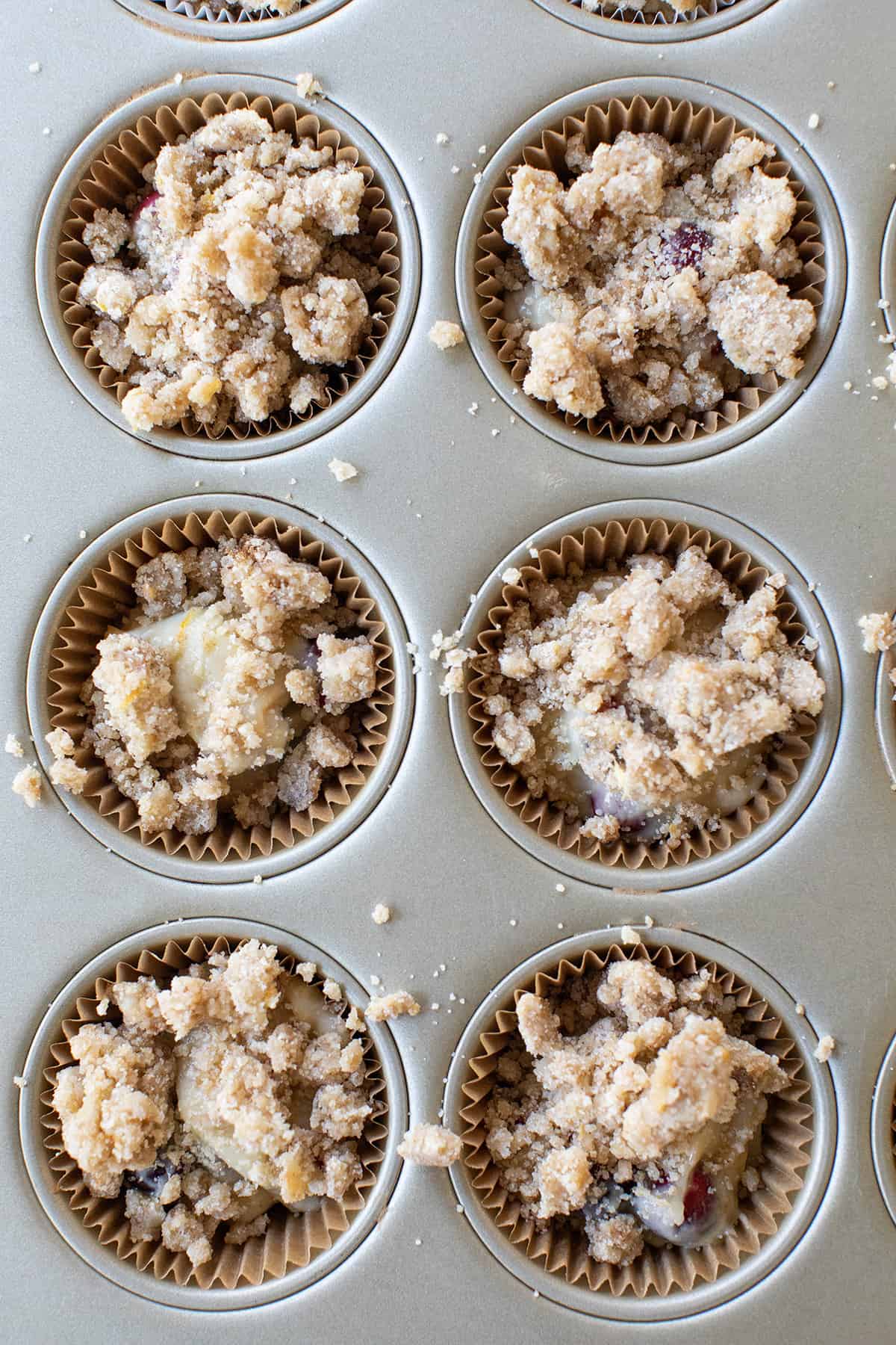 Muffin batter with streusel topping in a cupcake tin.