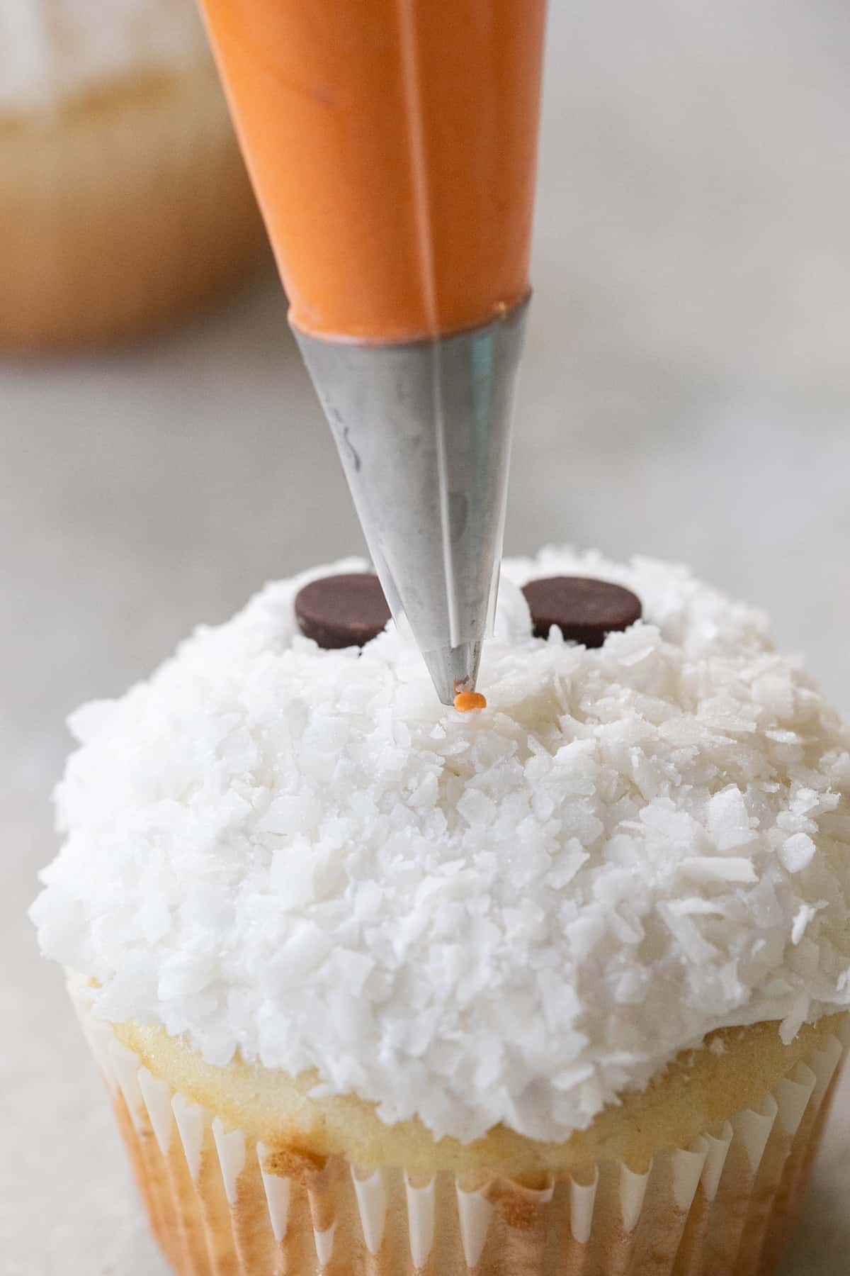 Making a small orange carrot nice with frosting.