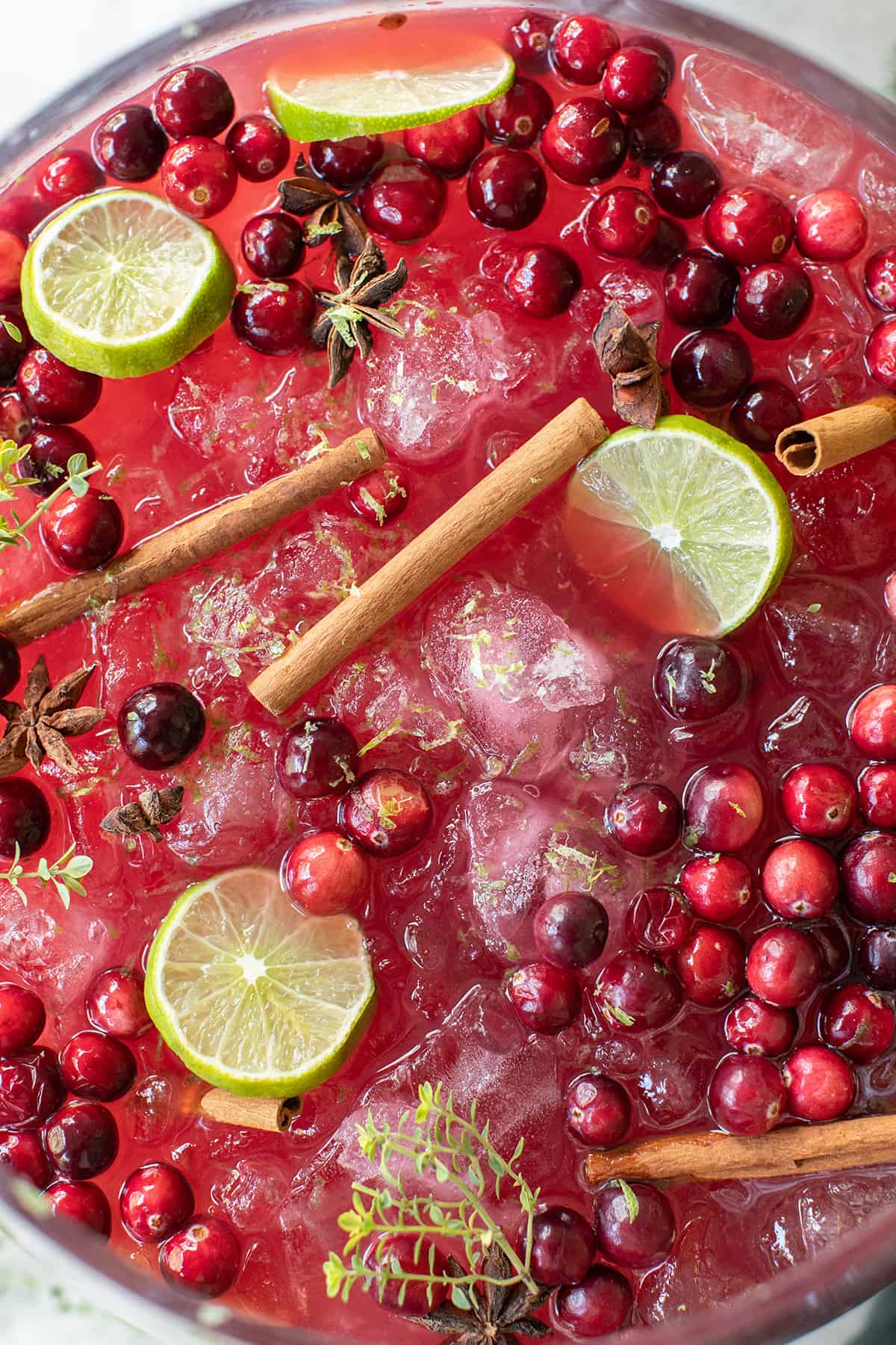 A Christmas drink with cinnamon sticks, limes, cranberries and thyme.