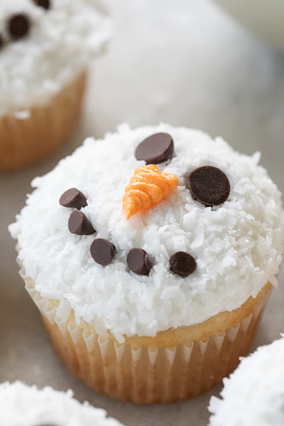 Coconut cupcake with a snowman face.