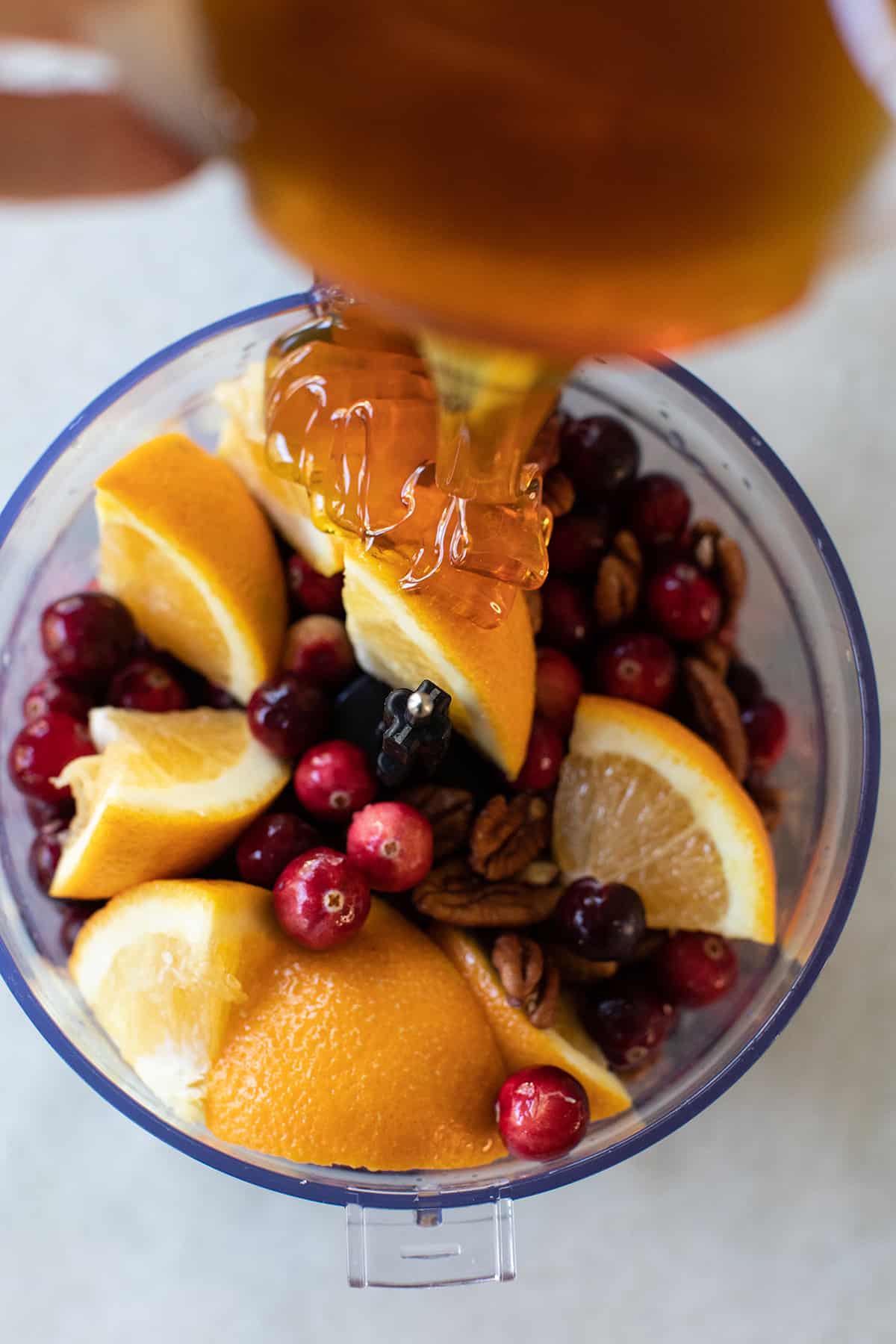 Pouring honey into cranberries and oranges.