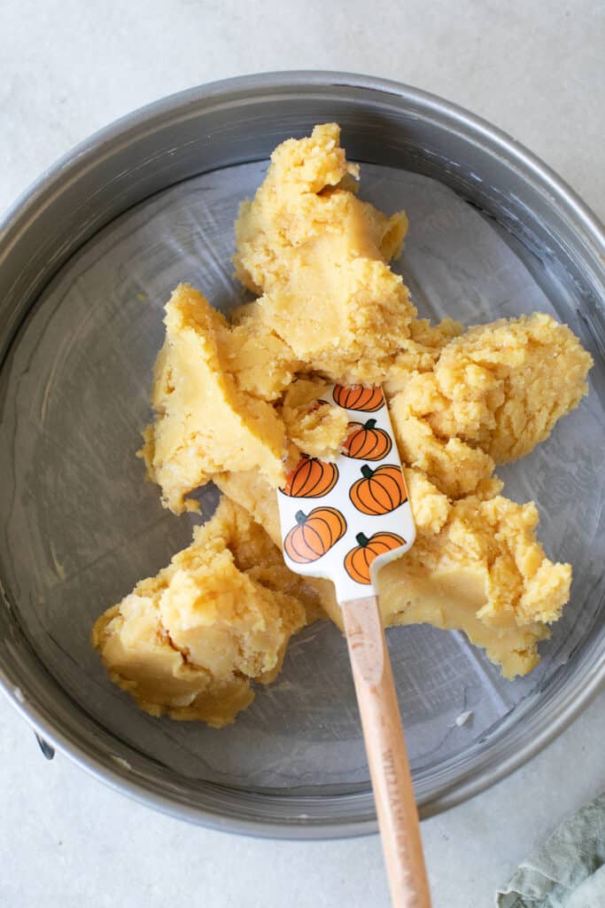 Spreading gooey butter cake mix on the bottom of a spring fold pan.