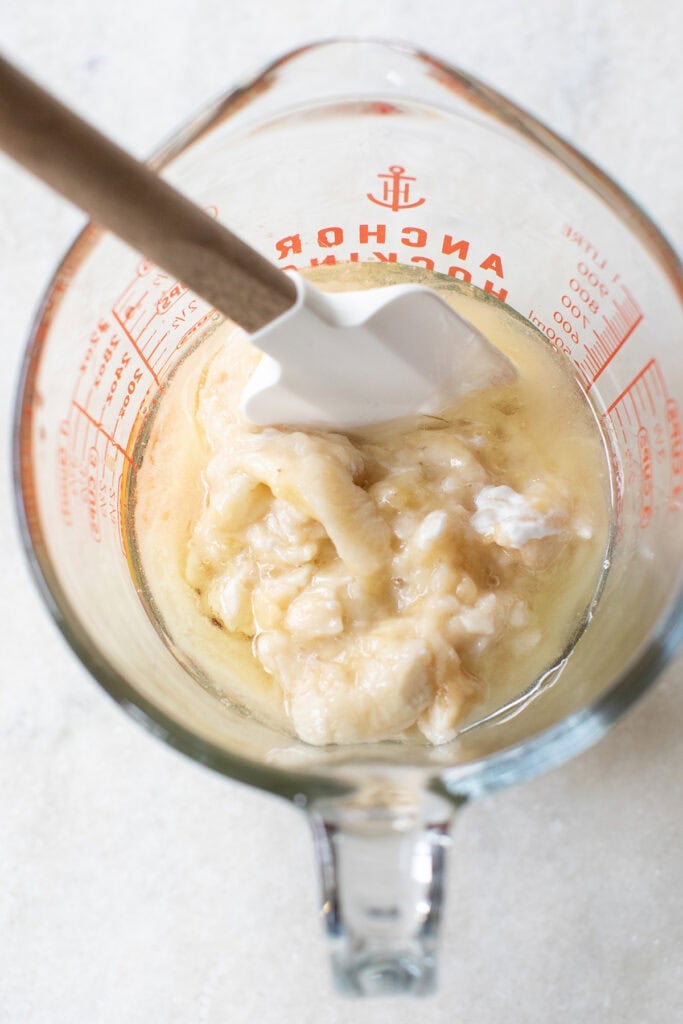 Mashed bananas and sour cream in a measuring cup.