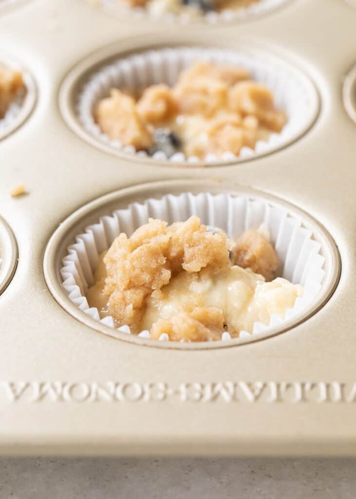 Streusel sprinkled over blueberry banana muffin batter.