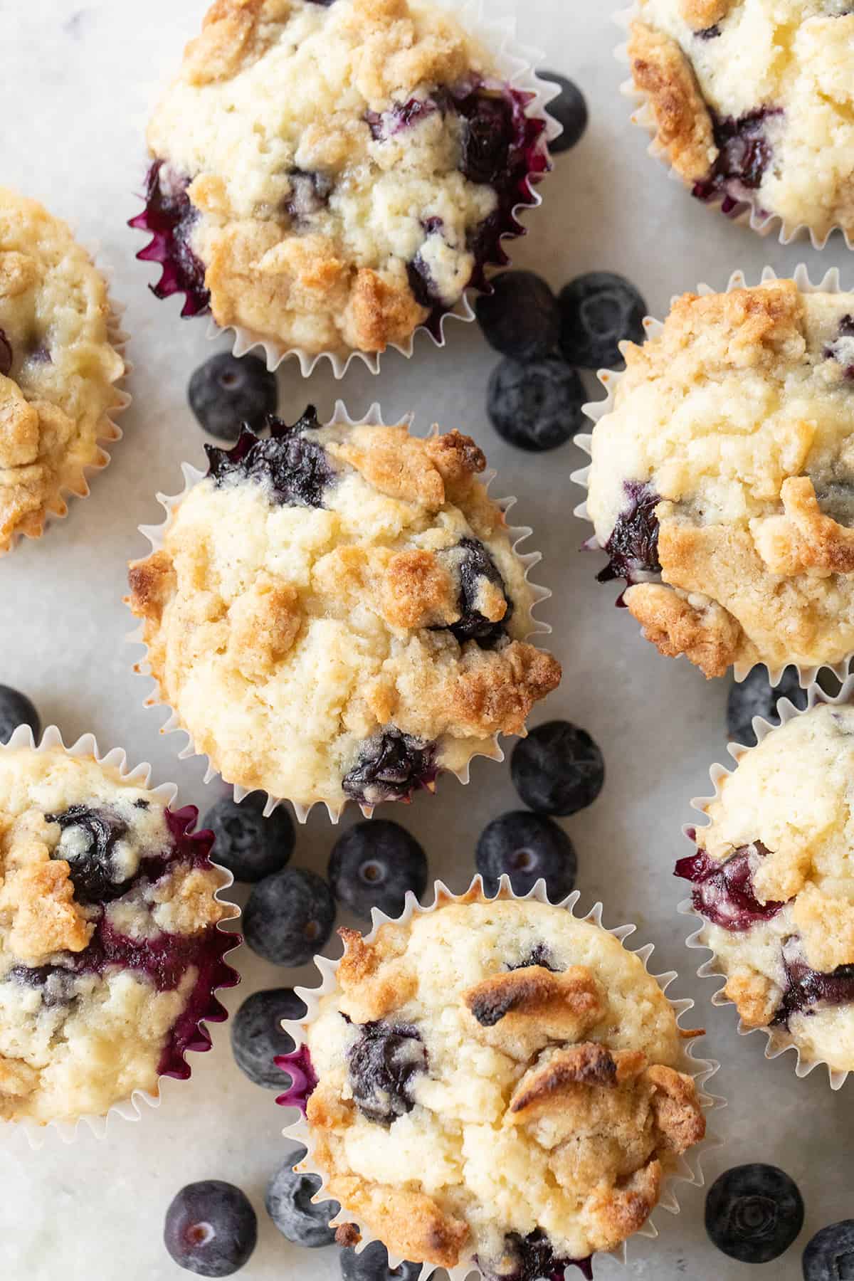 Blueberry banana muffins on a table with fresh blueberries. 