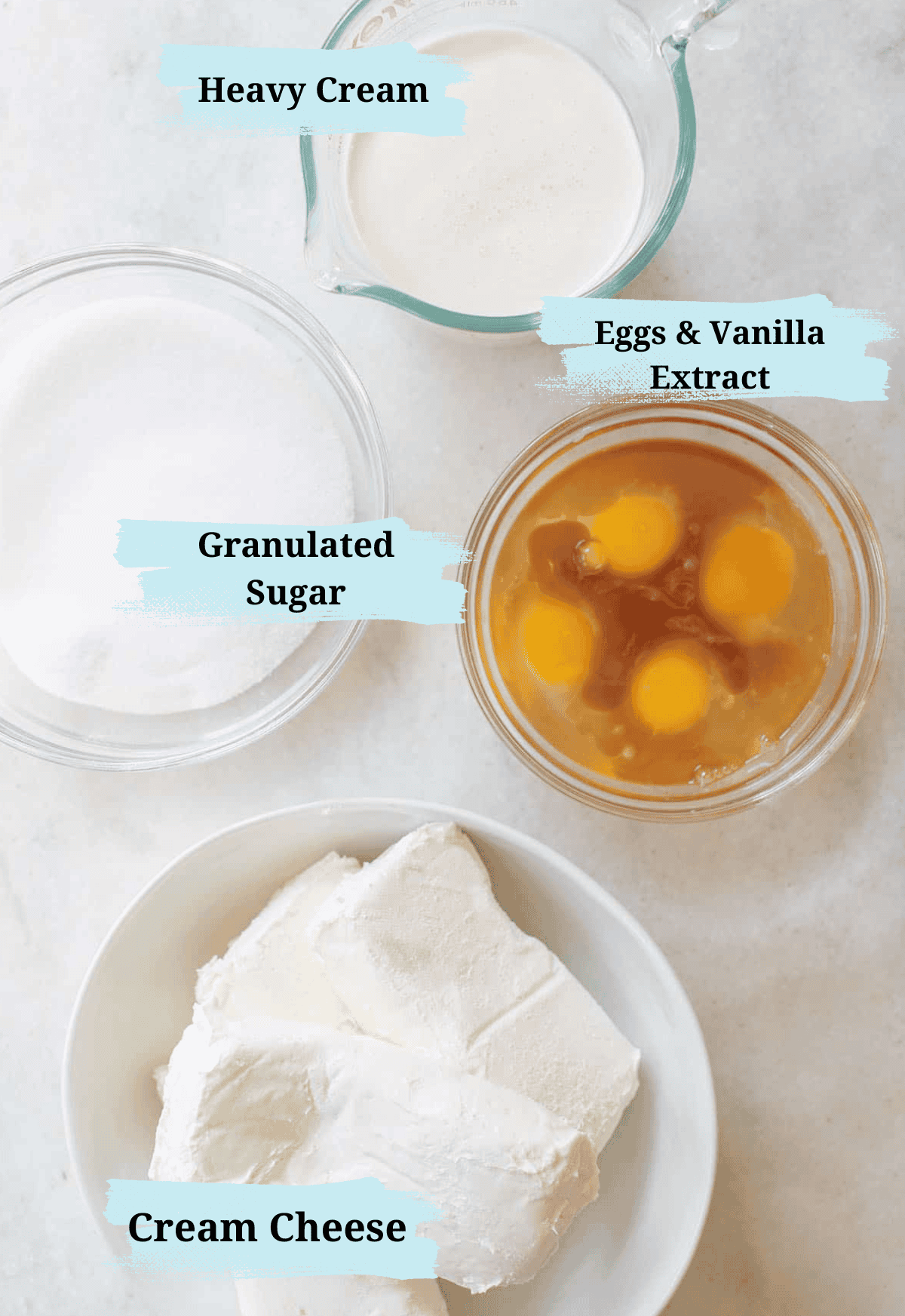 Heavy cream, sugar, eggs and cream cheese in bowls to make a homemade cheesecake recipe. 