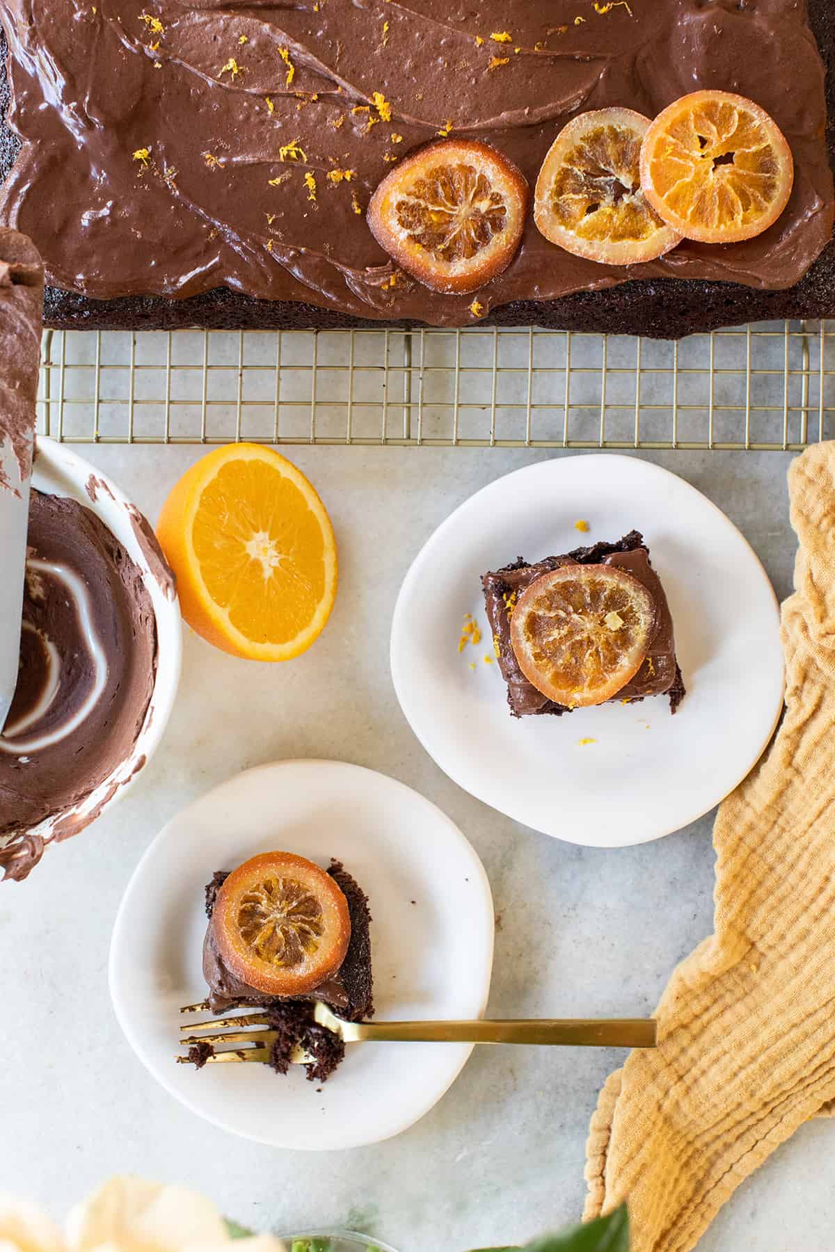 Orange chocolate cake slices with candied orange slices on white plates.