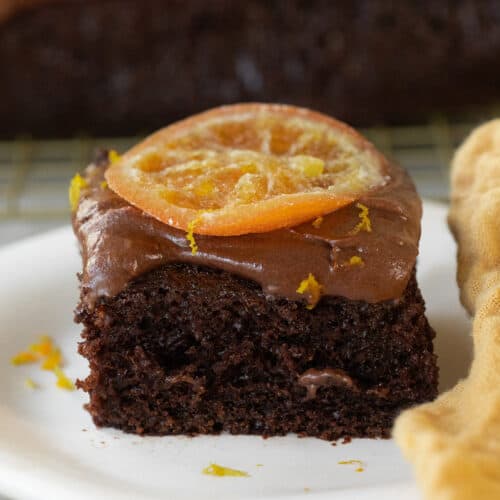A fluffy chocolate orange cake slice with a candied orange on the top.