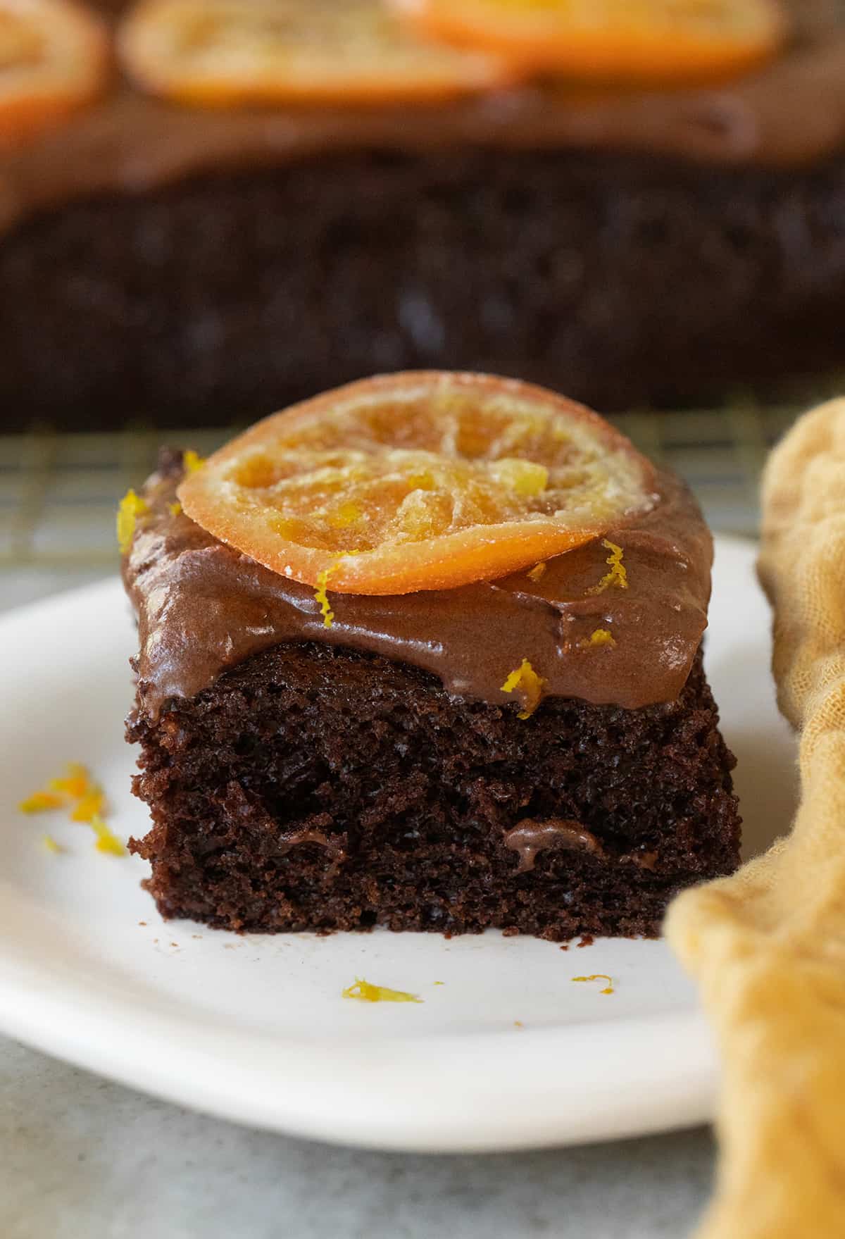 A fluffy chocolate orange cake slice with a candied orange on the top.