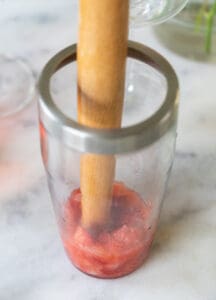 mudding strawberries in a cocktail shaker.