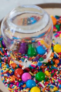 Dipping a shot glass into a bowl of sprinkles.