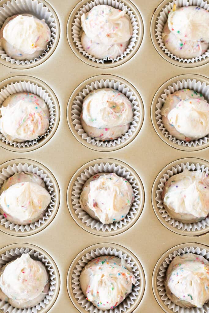 A filled cupcake tin with confetti cupcake batter.