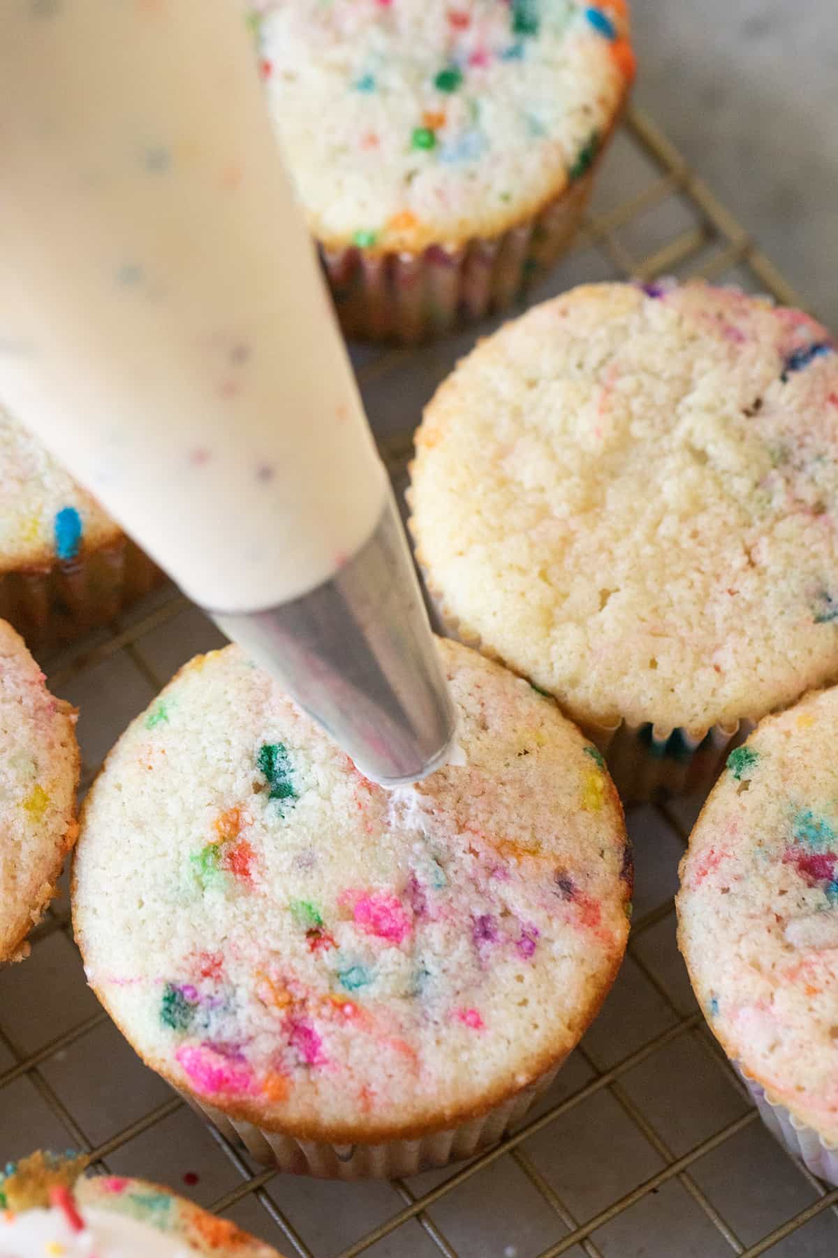 Piping bag fitted with round tip and filled with buttercream frosting.