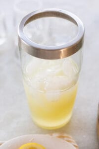 Cocktail shaker filled with ice, lemon juice, vodka and simple syrup.