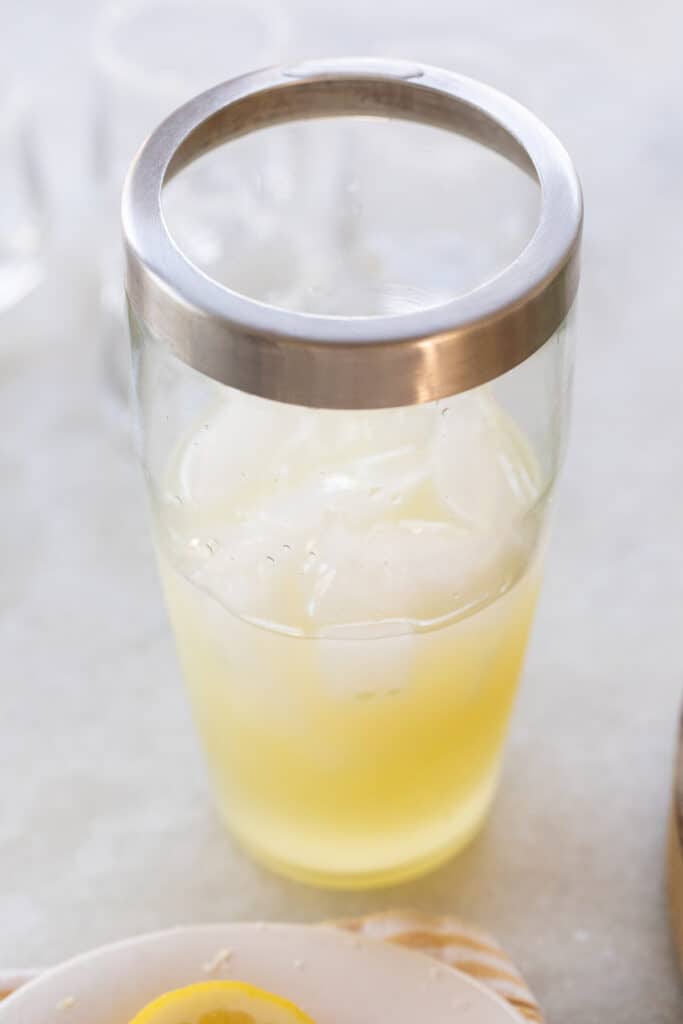 Cocktail shaker filled with ice, lemon juice, vodka and simple syrup.