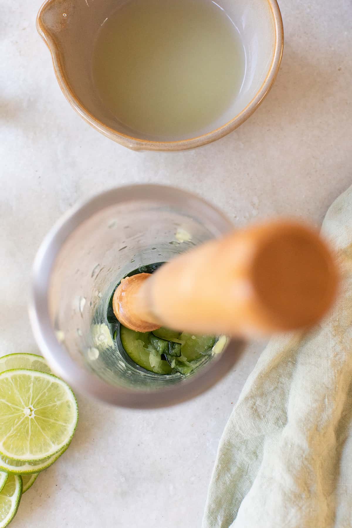 Muddling fresh cucumber in a cocktail shaker.