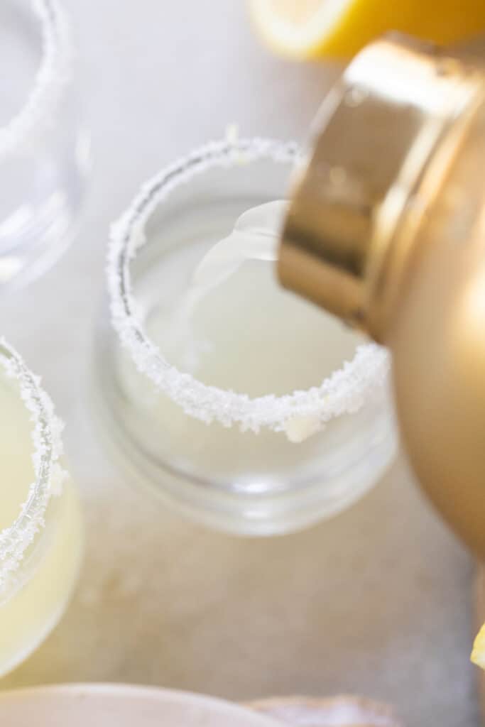 Pouring lemon vodka mixture into shot glasses