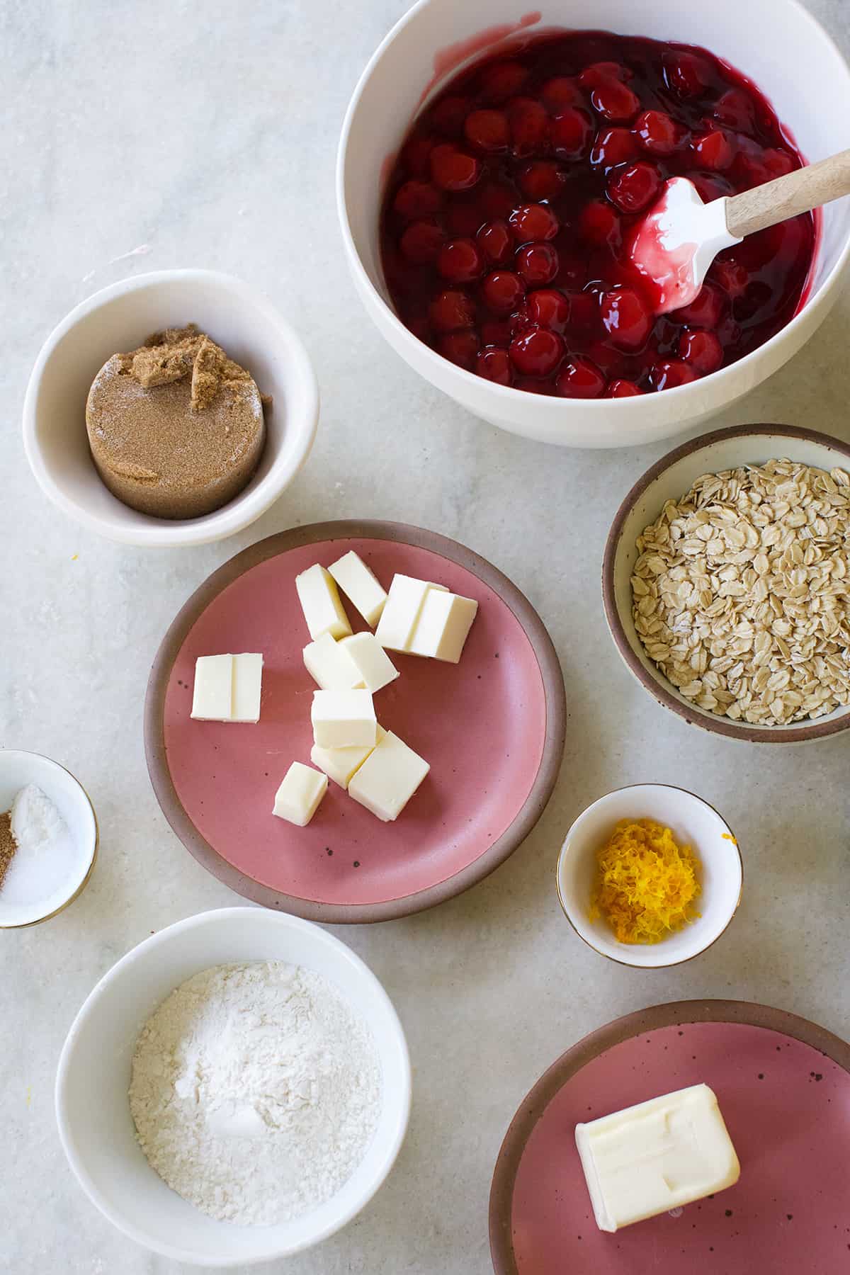 Cherry filling, butter, orange zest, rolled oats, brown sugar, nutmeg in bowls.