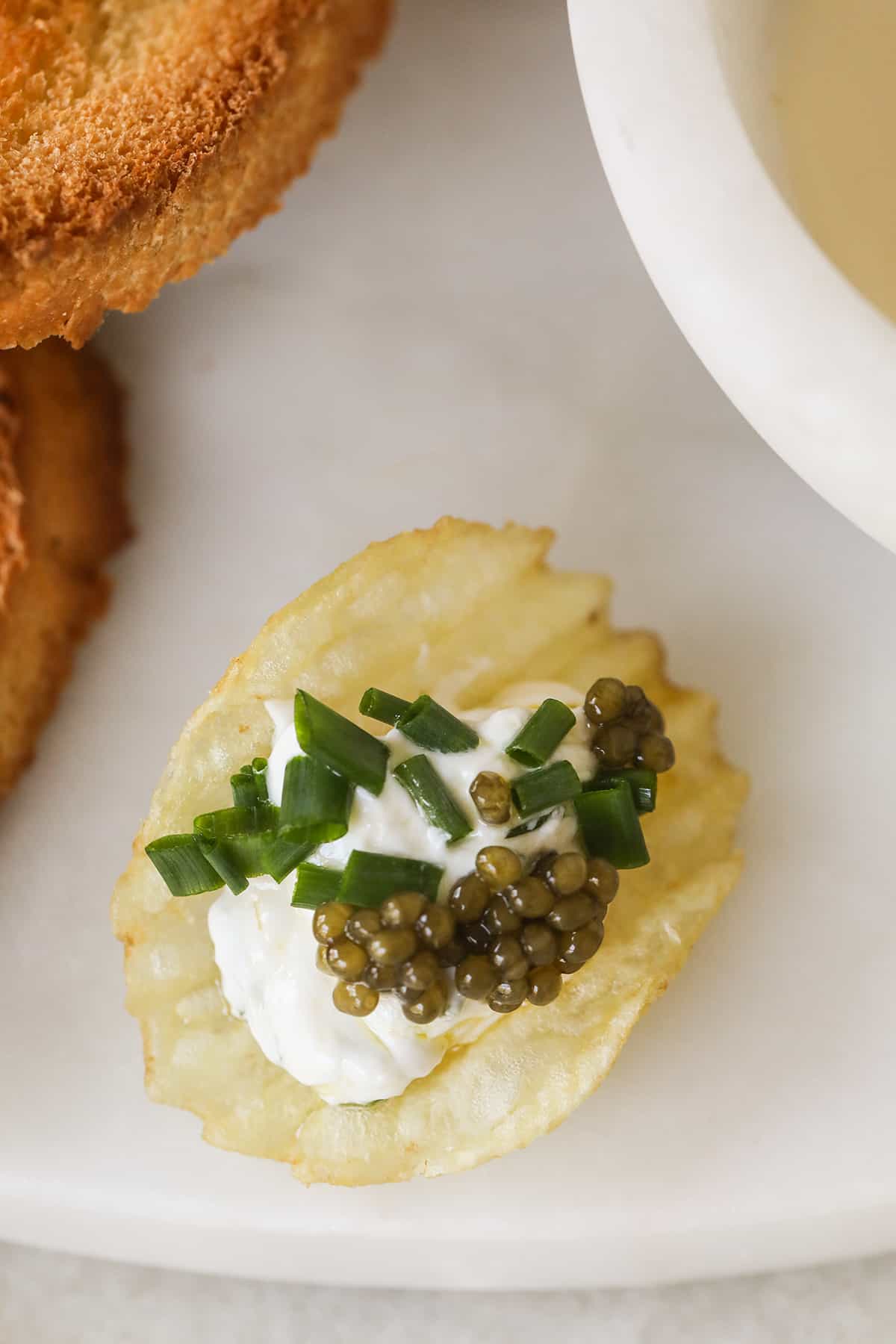 Potato chip with sour cream, chives and caviar.