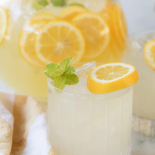 Mint lemonade in a glass with ice, garnished with a lemon slice and mint sprigs.