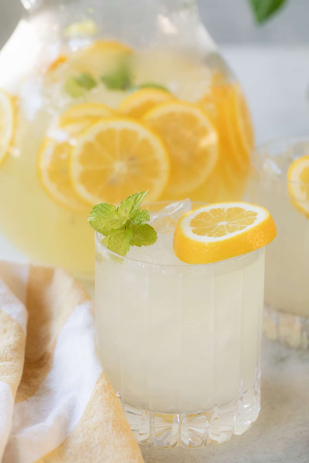 Mint lemonade in a glass with ice, garnished with a lemon slice and mint sprigs.