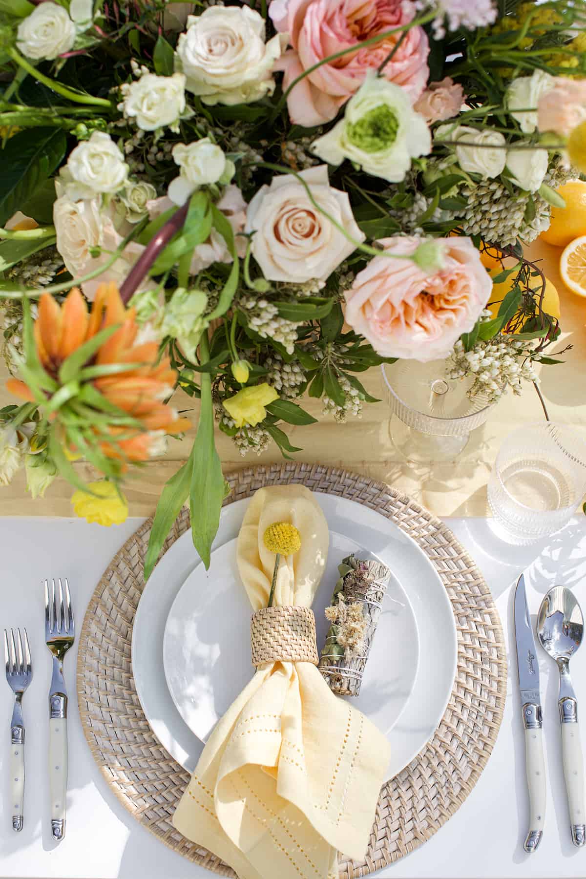 Spring table setting with flowers, lemons and sage.