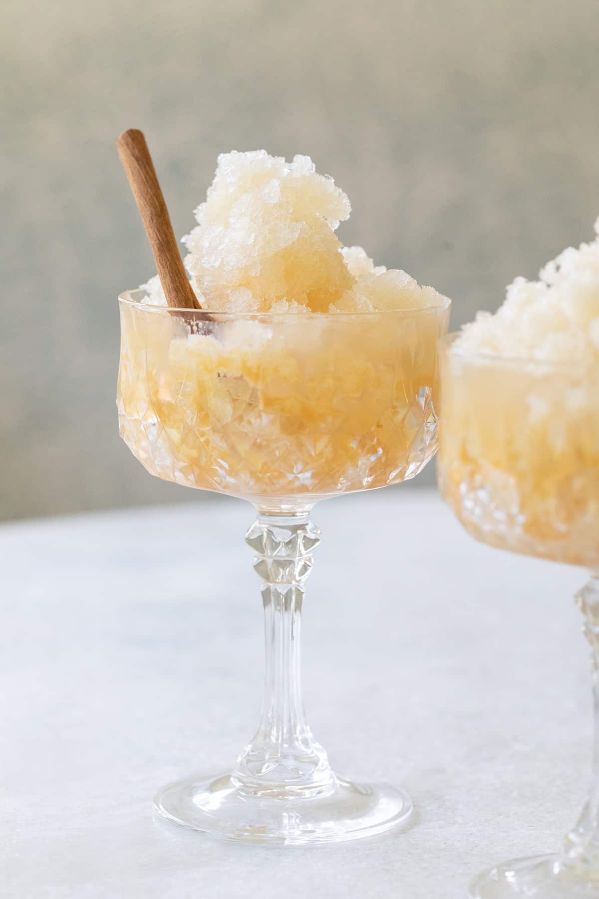 Appel cider slushie in a glass with a cinnamon stick. 