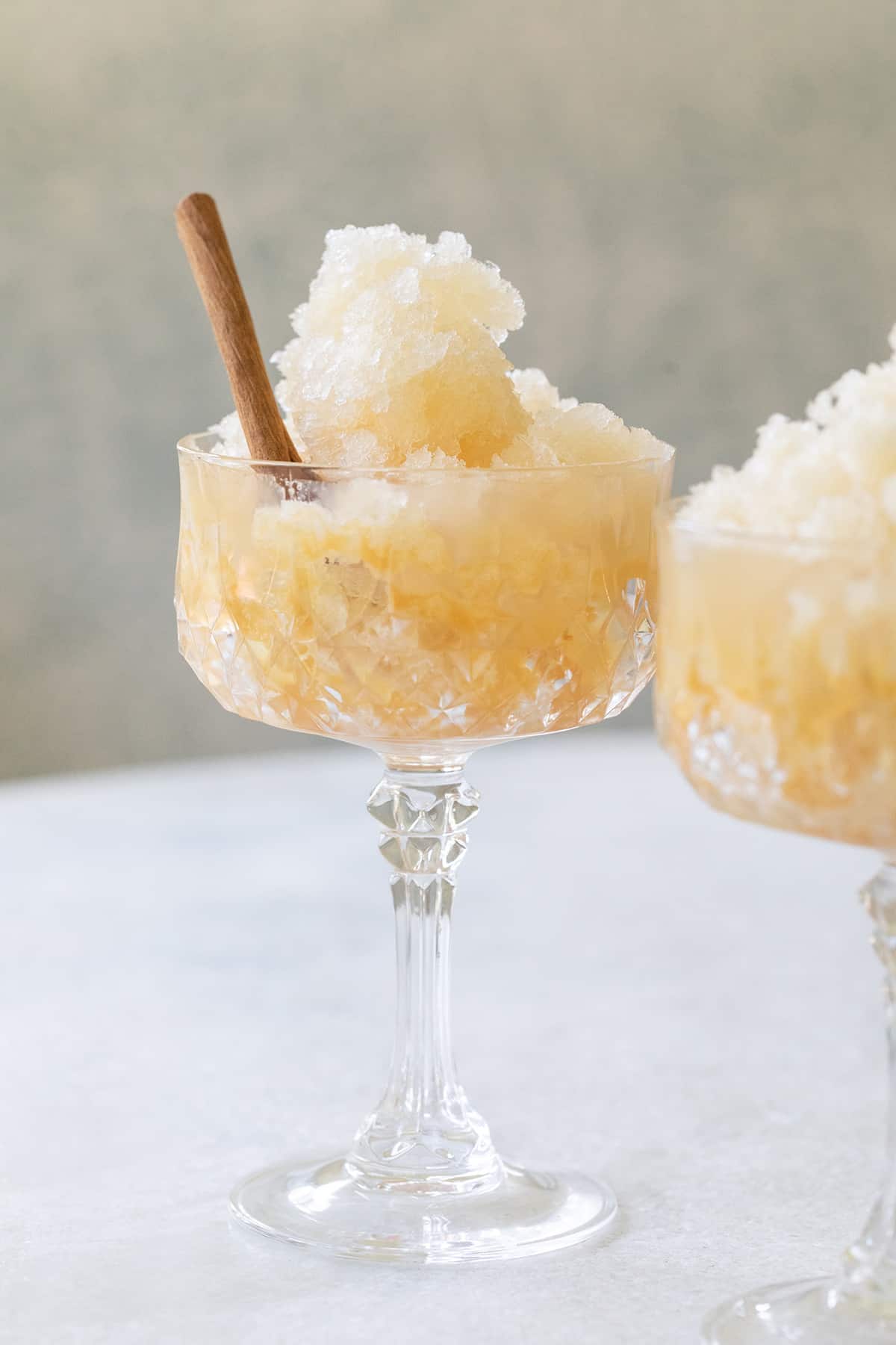 Appel cider slushie in a glass with a cinnamon stick.