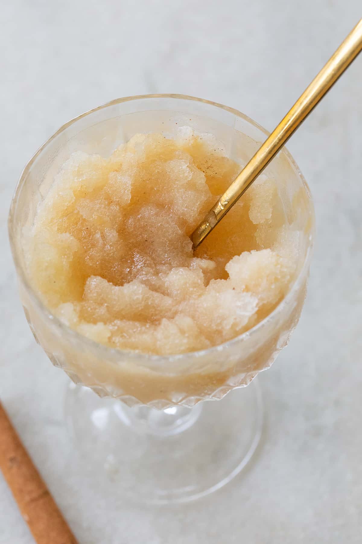 Frozen apple cider dessert in a glass with a gold spoon.