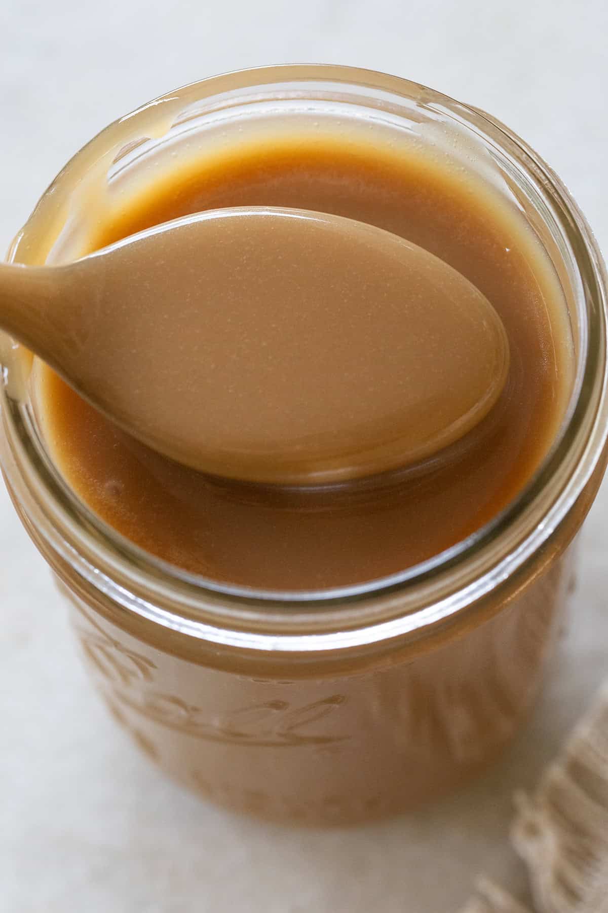 Creamy homemade caramel sauce in a glass jar.