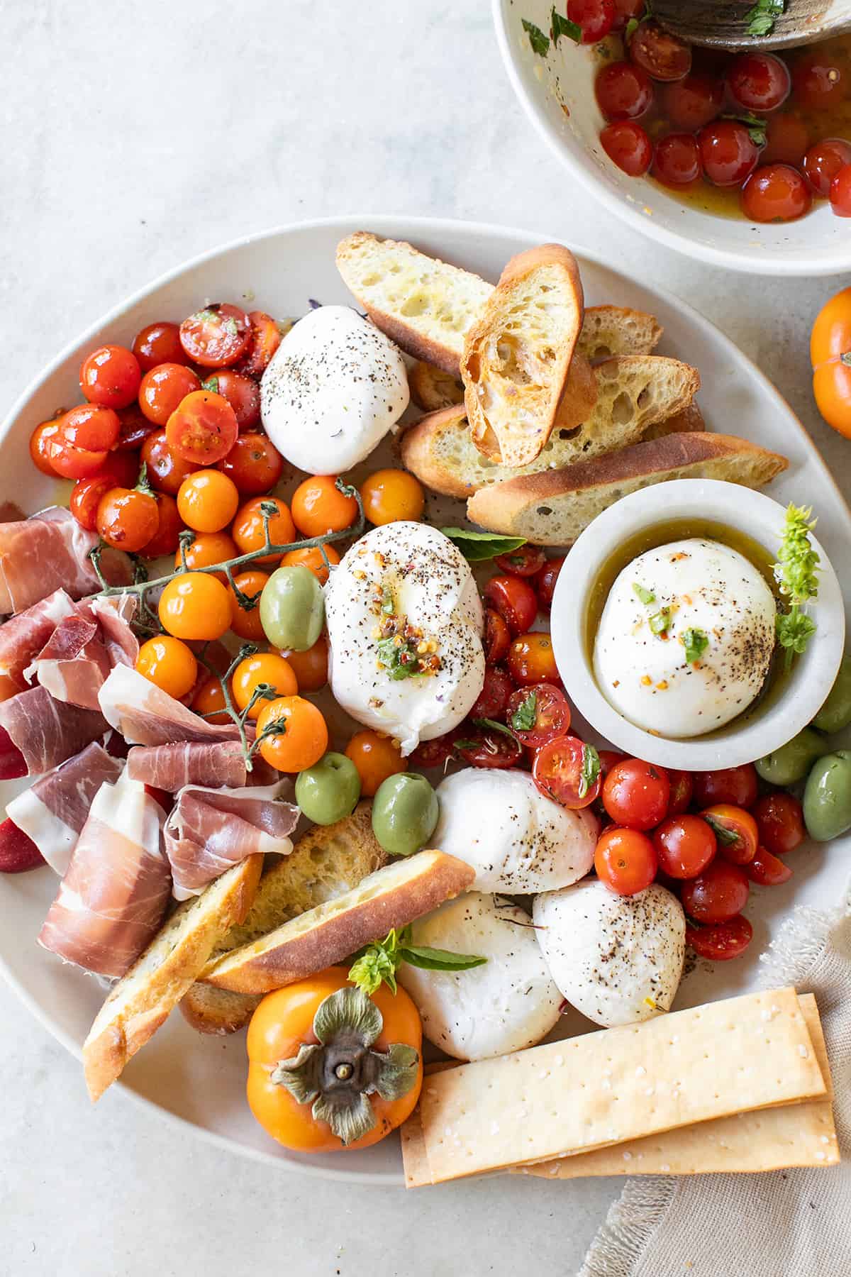 Burrata Platter with marinated tomatoes, crackers, olives and crostini.