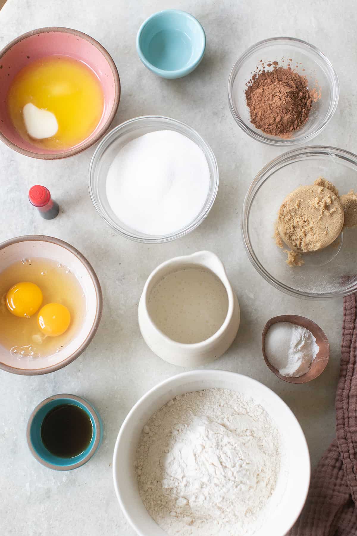 Eggs, buttermilk, vanilla, brown sugar, butter, flour, vanilla and red food coloring in small bowls.