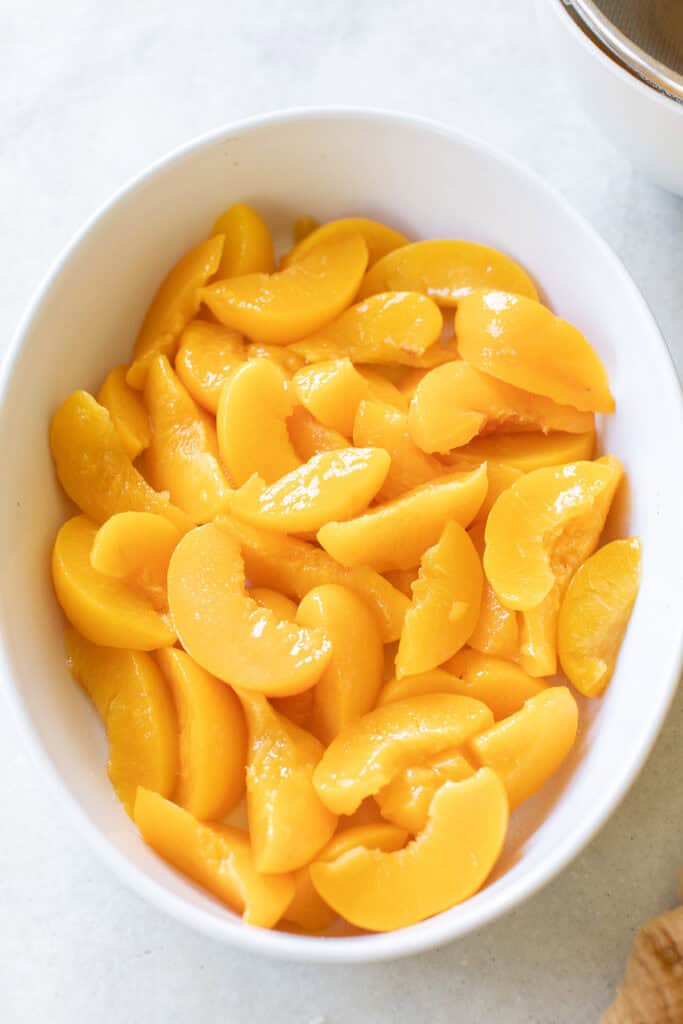 Canned peaches layered in an oval dish.