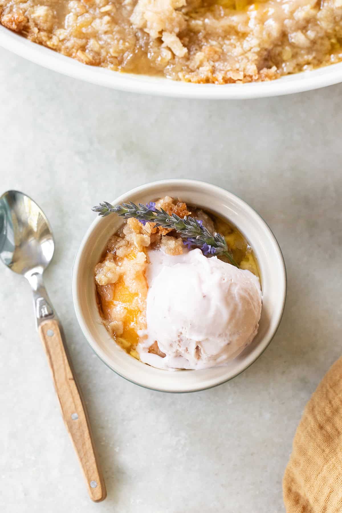Canned peach crisp served in a bowl with ice cream.