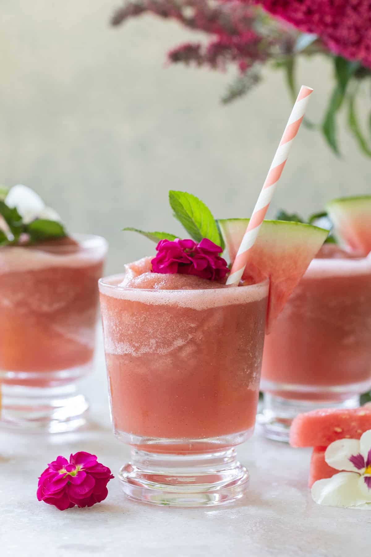 Easy watermelon frose with straws and flowers on a tray to serve for a summer gathering. 