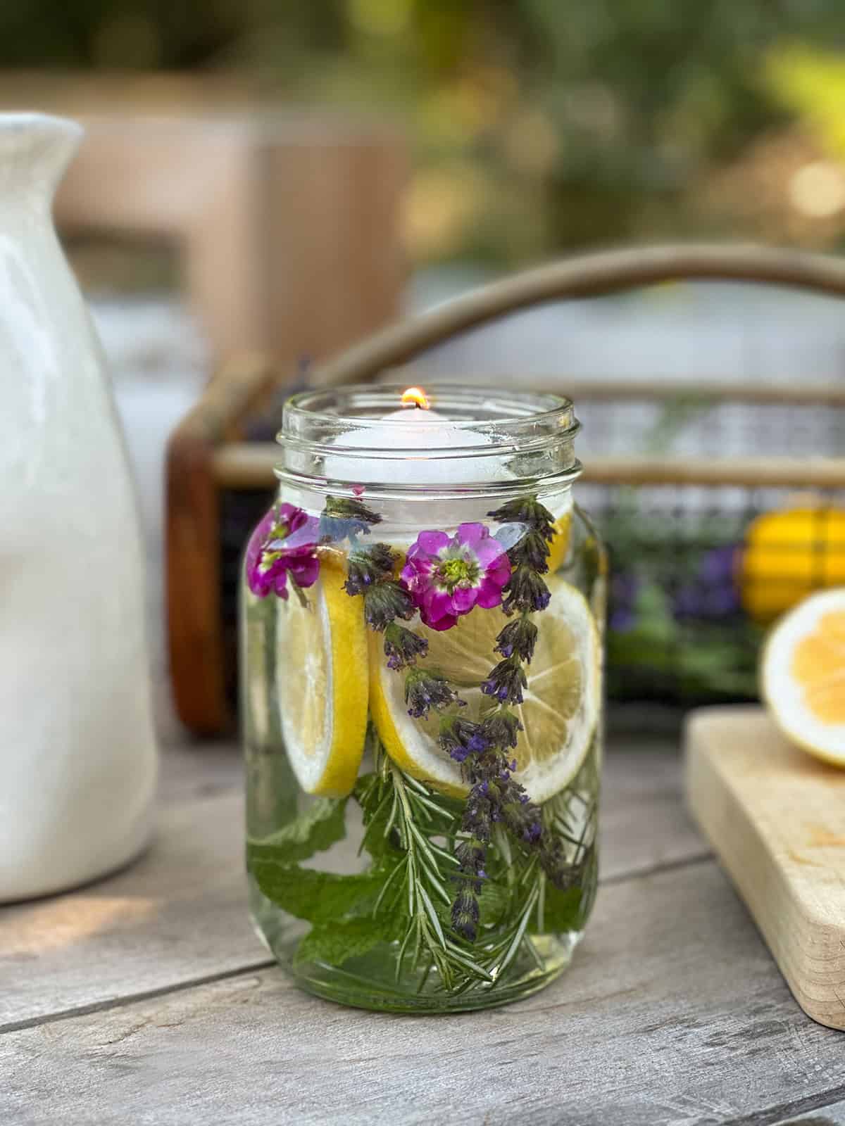 Mason jar filled with water, citronella oil, herbs and lemon slices. 