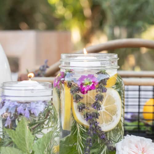 Citronella candle in jar with oil, herbs and a floating candle over the top.