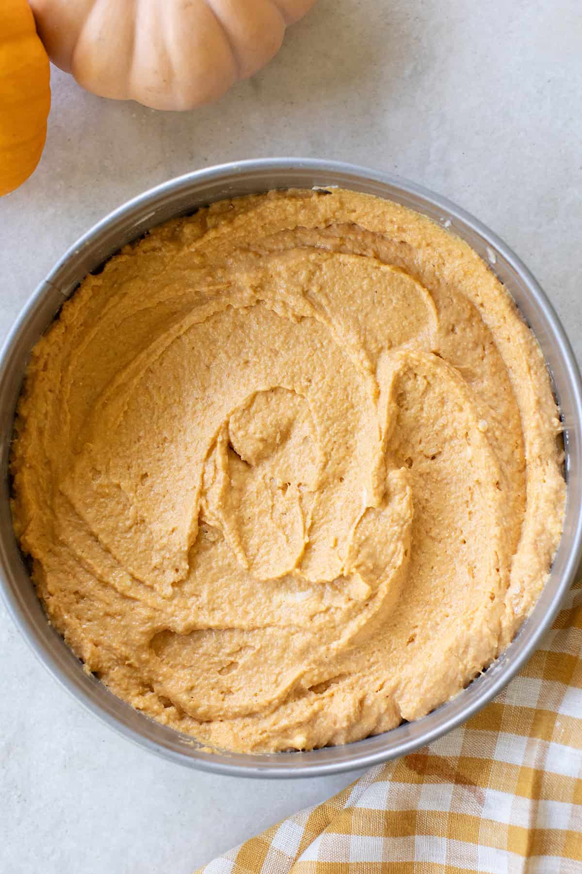 Pumpkin cornbread batter in a round pan.